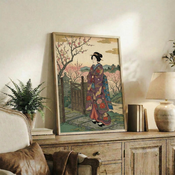 May include: Japanese woodblock print artwork in light wood frame showing woman in colorful kimono standing by wooden gate with cherry blossoms, displayed on rustic wooden sideboard alongside books, ceramic vase, and fern plant in neutral-toned living room setting with beige chair visible.