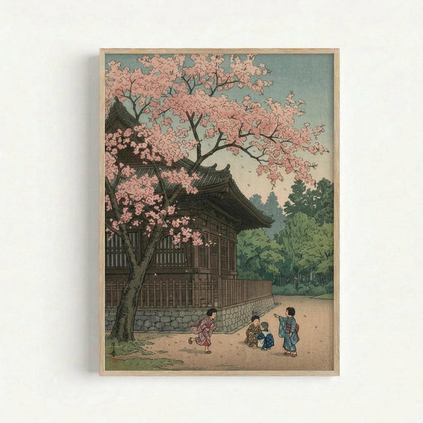 May include: Framed vintage Japanese woodblock print showing cherry blossoms in full pink bloom over a traditional temple building with curved rooflines. Three small figures in colorful kimono play beneath the flowering tree on a dirt path. Lush green trees fill the background under a pale blue-green sky. The artwork has muted, natural colors typical of early 20th century printmaking, displayed in a simple light wood frame against a white wall.