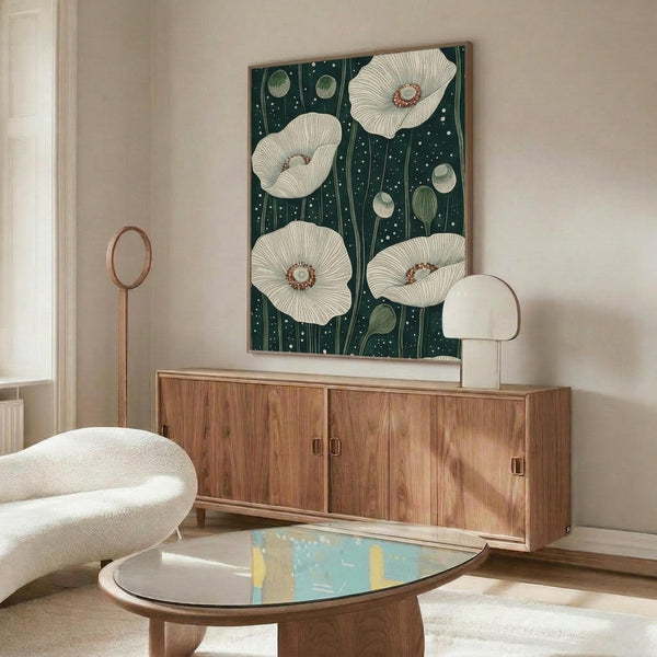 May include: Framed botanical poster with large white poppies and green seed pods on dark teal background with white dots, displayed above mid-century modern walnut credenza in bright living room with cream curved chair, brass floor lamp, white table lamp, and oval glass coffee table on beige rug.