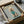 May include: Framed poster print in cardboard box with protective wrapping, showing cream-colored poodle wearing teal knit sweater against gray background with gold "DOGUE" text at top, black frame with white matting, surrounded by brown packaging materials on white surface