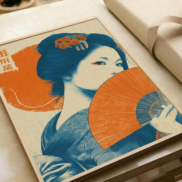 Japanese woodblock print style artwork featuring a geisha with dark blue hair adorned with orange flowers, holding an orange folding fan. She wears a blue patterned kimono against a cream background with orange circular elements. The print displays traditional ukiyo-e aesthetics with bold blue and orange colors, visible on white paper with printing materials nearby.