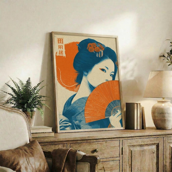 May include: Framed Japanese-style poster featuring a geisha with dark blue hair holding an orange folding fan, wearing blue patterned kimono against orange circular background with Japanese text, displayed on rustic wooden console table alongside books, ceramic vase, and fern plant in cozy living room setting
