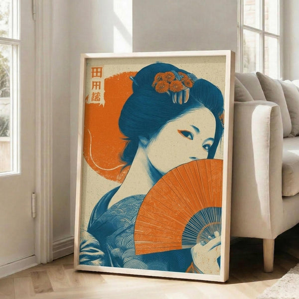 May include: Framed artwork featuring a Japanese woman with blue hair adorned with orange flowers, holding a vibrant orange folding fan. The vintage-style poster uses a blue and orange color palette with Japanese characters in the upper left corner. The piece is displayed in a light wood frame, leaning against a white wall next to a beige upholstered chair in a bright, naturally lit room with hardwood floors.