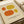May include: Framed art print featuring four abstract oval shapes in orange and yellow tones on cream background, displayed on white surface next to rolled paper tube. Print shows "ELLSWORTH KELLY" and "Girande, 1964" text at bottom in black letters within thin border frame.