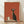 May include: Framed poster print displayed on wooden floor against white wall with natural lighting. Features stylized black cat with large round eyes sitting on shelf next to cream-colored coffee pot and small cup. Warm rust-orange background with minimalist illustration style. Light wood frame surrounds the artwork.