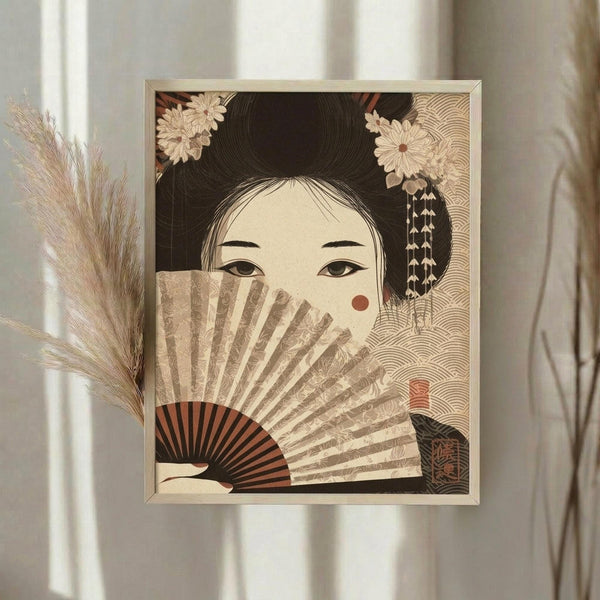 May include: Framed Japanese-style artwork showing a geisha with elaborate black hair adorned with cream flowers and dangling ornaments, holding a decorative fan that partially covers her face, displaying only her almond-shaped eyes and a red beauty mark on her cheek. The print features warm earth tones with intricate geometric patterns in the background. Displayed on a wall with dried pampas grass stems nearby and soft natural lighting from a window.