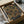 May include: Framed geometric art print featuring overlapping semicircular shapes in warm autumn colors - rust red, golden yellow, and olive green - on a dark background. The print sits in a wooden frame inside cardboard packaging with tissue paper, surrounded by wooden dowels and shipping materials on a desk surface.