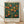 May include: Framed vintage-style botanical poster featuring orange fruit tree with lush green leaves against deep teal background, displayed on wooden floor against white wall with natural lighting and fabric shadows. Light wood frame surrounds artwork with exhibition text below the illustration.