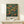 May include: Framed poster featuring orange fruit tree with lush green foliage against deep blue background, displayed on light wood surface with small white wrapped gift. Arts and Crafts style botanical illustration with "William Morris" and "Centenary Exhibition" text at bottom. Natural wood frame complements warm, earthy color palette.