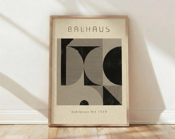 May include: Framed Bauhaus-style poster with geometric black and white design featuring curved and linear elements, displayed on light wooden floor against white wall with natural window lighting creating soft shadows