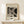 May include: Framed Bauhaus-style poster with geometric black and white abstract design featuring curved and angular shapes with fine line details, displayed on light wood surface alongside small wrapped gift with twine and dried botanicals against neutral wall