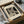 May include: Framed Bauhaus-style poster with bold geometric letter R design in black and beige, displayed in black frame inside cardboard shipping box with protective tissue paper and wooden corner guards on white surface