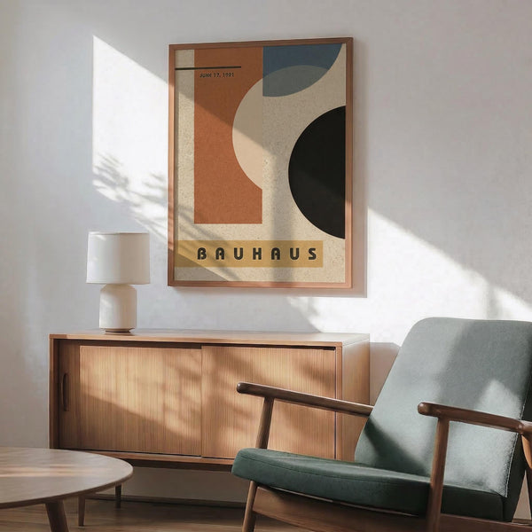 May include: Framed Bauhaus poster from June 17, 1921 featuring abstract geometric shapes in orange, blue, green, and cream colors, displayed above a mid-century modern wooden credenza with white ceramic lamp. Teal upholstered armchair with wooden frame sits nearby in bright, minimalist room with white walls and natural lighting casting dramatic shadows.
