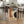 May include: Vintage Bauhaus exhibition poster dated June 17, 1921 featuring abstract geometric shapes in orange, cream, blue, and dark green colors, displayed on light wood floor against modern dining table with woven chairs in contemporary kitchen setting with white cabinets and natural lighting.