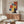 May include: Framed Bauhaus exhibition poster from 1922 featuring geometric shapes in red, blue, and yellow colors displayed above a walnut wood credenza in a modern living room. White sculptural chair and glass coffee table visible in foreground, with warm natural lighting creating reflections on surfaces.