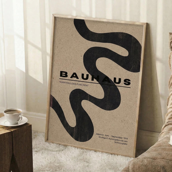 May include: Framed Bauhaus poster with abstract black curved shapes on beige textured background, displayed in bright room corner next to wooden stool with white coffee cup, sitting on white fluffy rug against white paneled walls with natural window light creating soft shadows.
