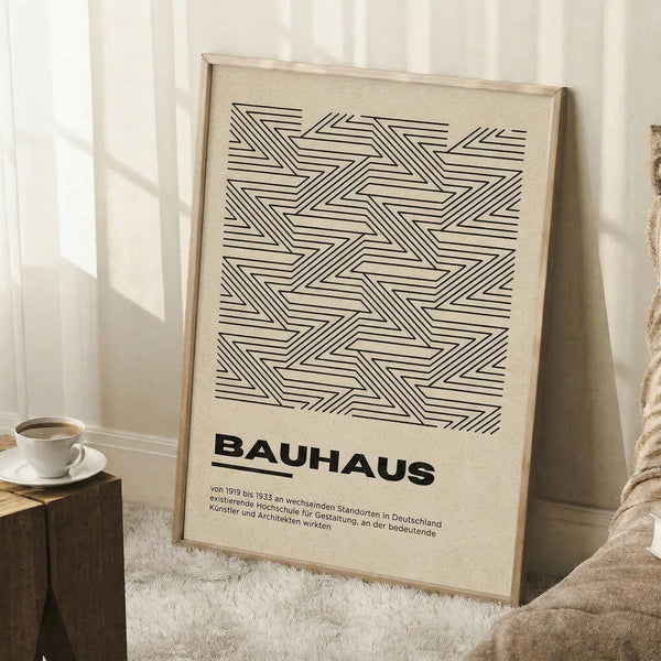 May include: Framed geometric poster with black linear zigzag pattern on beige background, displayed in bright room corner next to white coffee cup on wooden stool and cream textured blanket. Light wood frame casts soft shadows on white wall.