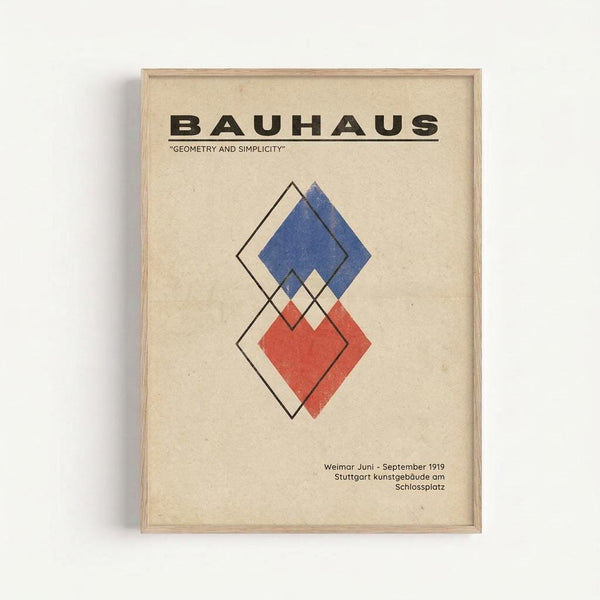 A framed Bauhaus poster with geometric diamond shapes in blue and red overlapping with outlined diamonds on cream textured paper. The word "BAUHAUS" appears in bold black letters at the top with "GEOMETRY AND SIMPLICITY" underneath. German exhibition text appears at the bottom. The poster is displayed in a light wood frame against a white wall.