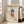 May include: Framed Bauhaus-style poster with geometric diamond shapes in blue and red on cream background, displayed on wooden floor next to beige sofa in bright living room with white walls and windows