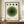 May include: Framed Bauhaus-style poster with concentric green circles and four dots above, displayed on wooden sideboard next to white ceramic vase and stacked books. Modern minimalist room with cream walls and panel molding. Vintage-inspired geometric art print in warm wood frame.