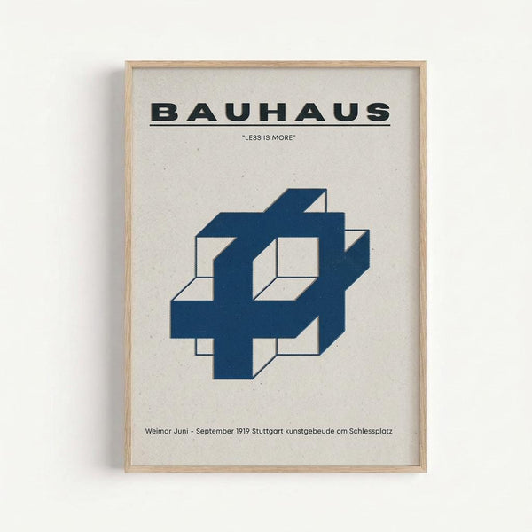 A framed poster with cream background featuring bold black "BAUHAUS" text at top, "LESS IS MORE" quote below, and a geometric blue 3D interlocking cube design in the center. German text appears at bottom. The poster is displayed in a light wood frame against a white wall, showing clean minimalist Bauhaus design principles with strong geometric shapes and limited color palette.