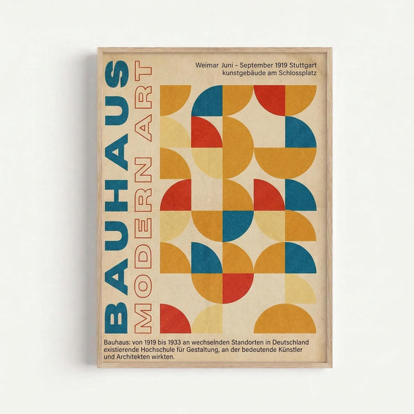 Framed poster with geometric Bauhaus-style design featuring colorful semicircles and quarter-circles in orange, blue, red, and yellow arranged in a grid pattern. Bold blue text reads "BAUHAUS" vertically on left side with red "MODERN ART" text. German text appears at top and bottom describing the Weimar art school from 1919-1933. Natural wood frame against white wall.