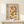 May include: Framed Bauhaus poster with geometric design featuring colorful circles and semicircles in orange, blue, red, and yellow arranged in a grid pattern. German text "BAUHAUS MODERN ART" appears vertically on left side. Wooden frame sits on light wood console table against white wall, with small wrapped gift beside it.
