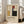 May include: Framed Bauhaus poster with geometric design featuring colored rectangles in red, blue, yellow, and black on cream background, displayed in white frame leaning against wall next to beige sofa in bright living room with hardwood floors and large windows