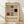 May include: Framed Bauhaus poster with geometric shapes in black, red, and gray on cream background, leaning against white wall on light wood floor. Features grid patterns, squares, rectangles, and lines in modernist style with "BAUHAUS WEIMAR JULI-SEPT 1919" text at bottom in thin wooden frame.