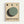 Minimalist poster featuring geometric circles in black, dark gray, and sage green arranged on cream background. Three small circles aligned at top with larger overlapping circles below creating layered effect. Bold black text reads "BAUHAUS" with "WEIMAR JULI - SEPT 1919" underneath. Natural wood frame against white wall. Clean modernist design with muted earth tones and simple typography reflecting Bauhaus aesthetic principles.