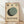 May include: Framed Bauhaus-style poster with geometric design featuring overlapping circles in sage green, dark green, and black on cream background. Three small circles aligned at top in gradient from black to light green. Bold black text reads "BAUHAUS WEIMAR JULI - SEPT 1919" at bottom. Light wood frame sits on wooden floor against white wall with soft natural lighting and shadows.
