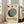 May include: Framed Bauhaus-style art print leaning against white wall next to beige sofa. Poster features cream background with geometric shapes - three small circles in black, teal, and sage green at top, large overlapping circles in sage green and dark teal below, black text reading "BAUHAUS" and "WEIMAR JULI-SEPT 1919" at bottom. Natural wood frame, bright room with large windows.