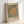 May include: Framed Bauhaus-style poster with vertical black stripes and tan circle, displayed against white wall. Cream textured background with "bauhaus," "weimar," and "juli sept 1919" text at bottom. Natural wood frame, minimalist geometric design in neutral earth tones.