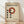 May include: Framed Bauhaus-style poster with cream background featuring bold black "BAUHAUS" text, red-orange circle, and geometric black dots arrangement. Light wood frame leaning against white wall on natural wood floor with soft window light creating shadows.