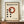 May include: Framed Bauhaus-style poster with cream background featuring red circle and black dots in geometric arrangement, displayed on wooden sideboard next to white ceramic vase and stacked books against white paneled wall
