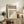 May include: Framed Bauhaus poster with black geometric circles and "Form Follows Function" text displayed on rustic wooden sideboard in neutral-toned living room. Cream upholstered chair, potted fern, ceramic vase, and stacked books create warm, minimalist styling around the vintage-inspired design print in natural wood frame.