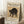 May include: Framed vintage-style poster featuring a black cat with arched back and hissing expression, displayed against white paneled wall. The artwork shows Japanese-inspired illustration on aged beige background with museum attribution text below. Scene includes wooden side table with white coffee cup, textured white rug, and beige knit throw blanket for scale reference.