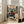 May include: Framed anime-style poster leaning against white wall next to beige sofa in bright room with windows. Shows character with dark hair in red and blue clothing wielding sword in mountainous landscape. Japanese and English text at top reads "Samurai Champloo" and "The Revolution of a Generation." Natural wood frame, vintage-inspired art style with muted earth tones.