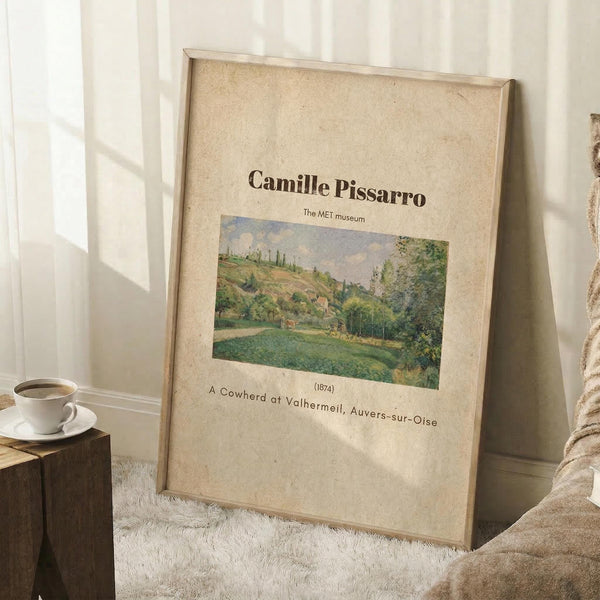 May include: Framed vintage-style poster featuring a Camille Pissarro landscape painting of green rolling hills and countryside, displayed in a cozy room setting with white walls, wooden cube side table holding a white coffee cup, and beige textured rug. The artwork shows pastoral scenery in soft greens and earth tones with museum attribution text.