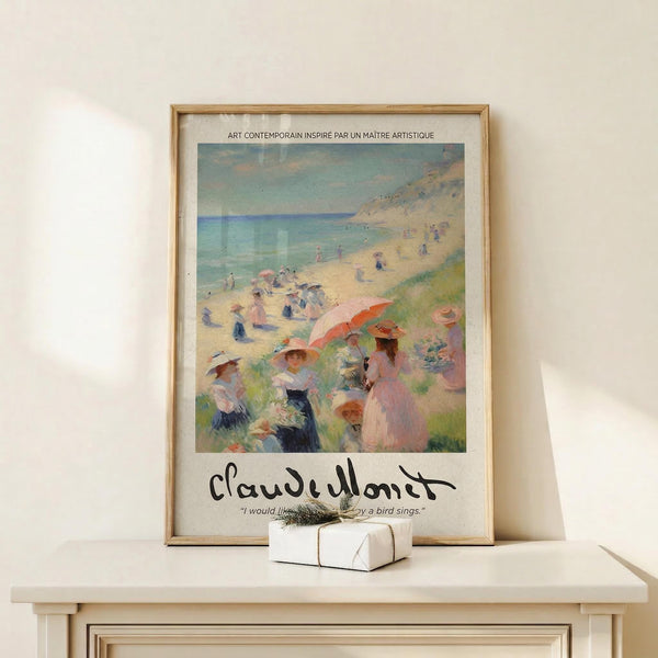 May include: Framed poster print featuring an impressionist beach scene with people in period clothing on sandy shore, turquoise water and cliffs in background. Poster shows soft brushstrokes in blues, pinks, and yellows with Claude Monet signature at bottom. Natural wood frame sits on light wooden surface beside small wrapped gift with twine, displayed against cream colored wall.