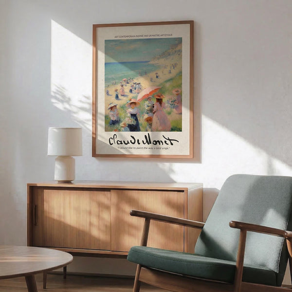 May include: Framed Claude Monet beach scene poster hanging on white wall above wooden sideboard with lamp. Print shows impressionist painting of people with parasols on sandy beach overlooking turquoise ocean. Warm sunlight streams across modern living room with sage green upholstered chair and round coffee table. Poster features cream matting with artist's signature below colorful seaside artwork.