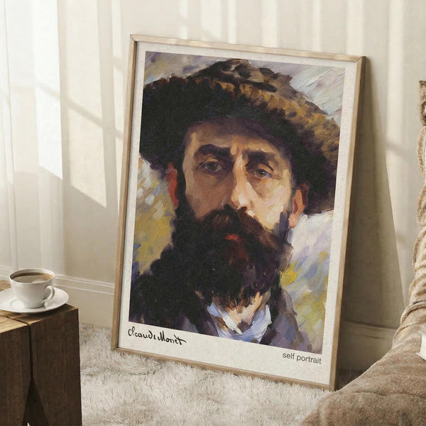 May include: Framed art print of a bearded man in a wide-brimmed hat, painted in impressionist style with visible brushstrokes in warm browns, yellows and purples. The vintage-style poster has a white border with handwritten signature below the portrait. Shown leaning against white paneled wall on a fluffy white rug, beside a wooden side table with white teacup and saucer.