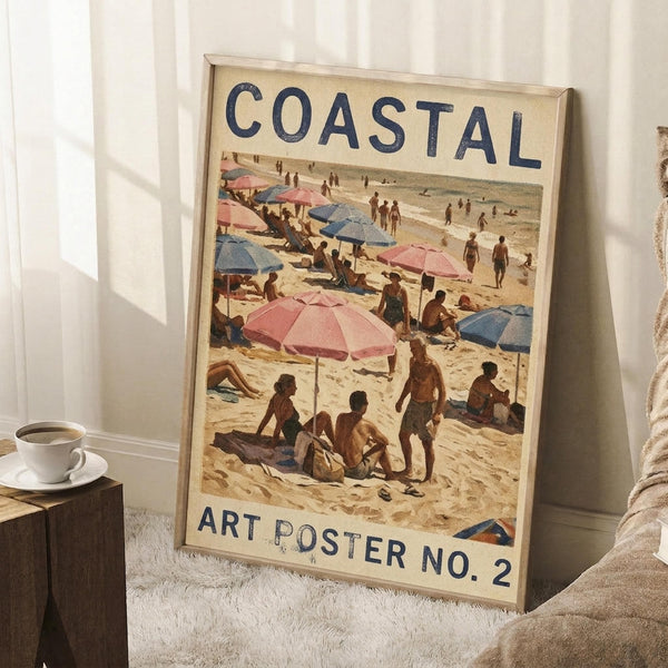 May include: Framed vintage-style beach scene poster leaning against white paneled wall on fluffy white rug. Shows sandy beach with pink and blue umbrellas, sunbathers, and people walking along shoreline. Text reads "COASTAL" at top and "ART POSTER NO. 2" at bottom in navy blue letters on cream background. Light wood frame, displayed next to wooden side table with white coffee cup and saucer, beige throw blanket visible at right edge.