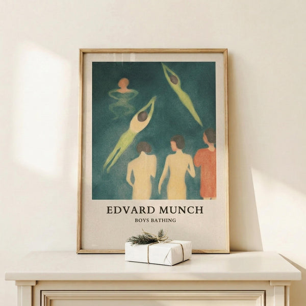 May include: Framed art print displaying figures in teal and yellow tones against a dark green background, showing swimming or bathing scene. Print has white matting in light wood frame, displayed on white wooden surface beside small wrapped gift with twine and evergreen sprig. Soft natural lighting creates gentle shadows on cream colored wall.