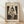 May include: Framed art print of Edvard Munch's "The Kiss" displayed on wooden floor against white wall with natural lighting. Print shows two nude figures embracing in black and white etching style, matted in cream with "EDVARD MUNCH" and "THE KISS" text, housed in natural wood frame.