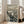 May include: Framed reproduction of Edvard Munch's The Scream artwork leaning against white wall in bright living room with beige sofa. Print shows iconic figure with hands to face on bridge, rendered in black ink with wavy sky lines and swirling patterns. Light wooden frame, approximately 2-3 feet tall, positioned on hardwood floor near large windows.