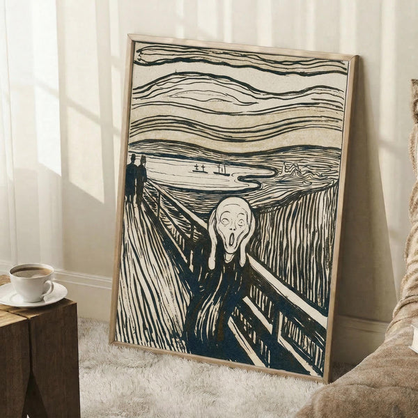 May include: Framed reproduction of Edvard Munch's famous expressionist artwork showing a skeletal figure with hands to face in an agonized scream, standing on a wooden bridge with two silhouetted figures in background. Swirling, wavy lines fill the sky in this black and white lithograph style print. Light wood frame leans against white wall corner next to cozy beige blanket and wooden side table with white coffee cup.