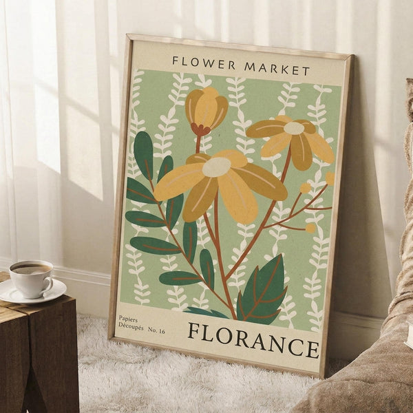 May include: Vintage-style botanical poster with sage green background featuring yellow daisy flowers and dark green foliage, displayed in light wood frame leaning against white wall corner. Scene includes white coffee cup on wooden block and textured cream blanket on white area rug, creating cozy home decor setting with natural window light.