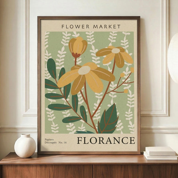 May include: Vintage-style botanical poster with yellow daisy flowers and green leaves on sage background, displayed in brown wooden frame on walnut credenza beside white ceramic vase and stacked books against cream walls with white trim molding.