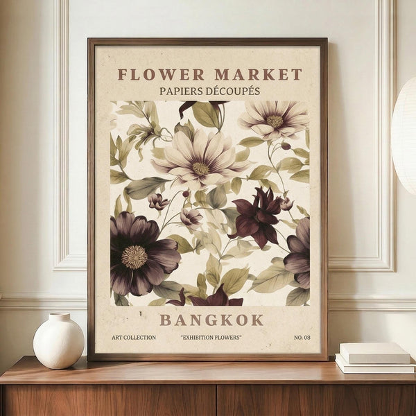 May include: Vintage-style botanical poster with cream background featuring purple and white flowers with green leaves, displayed in brown wooden frame on wood sideboard next to white ceramic vase and stacked books against white paneled wall